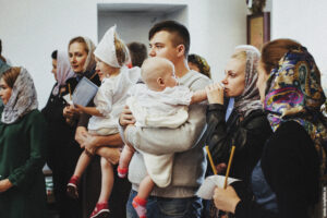 Мама успокаивает дочку во время крестин в Михаило-Архангельской церкви в Вертлино
